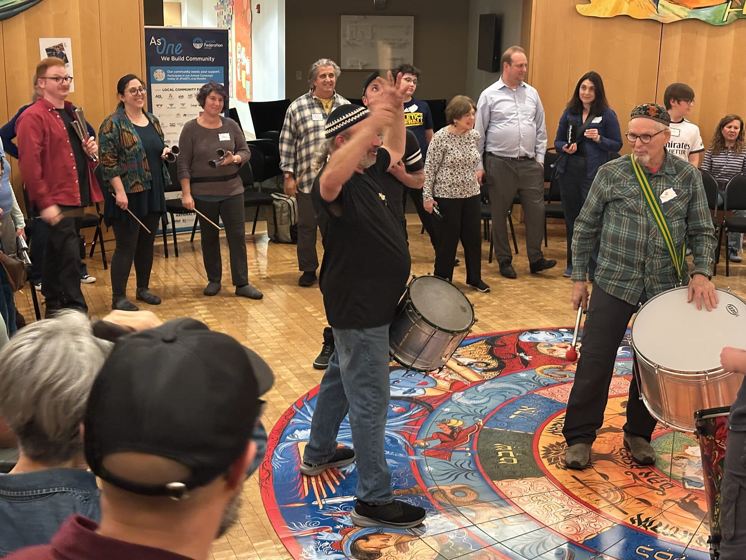 A diverse group of participants standing in a circle, hands clapping and singing.